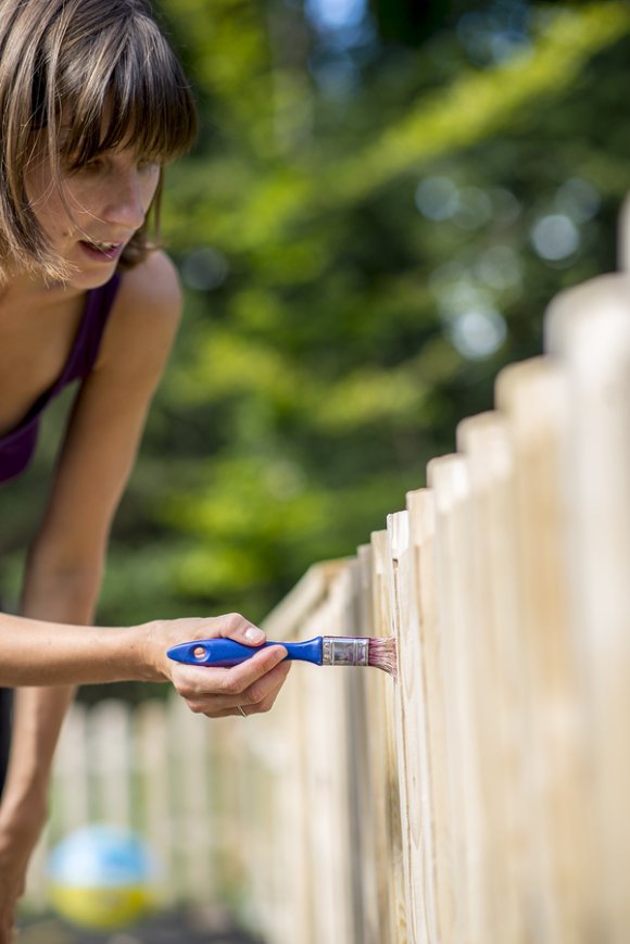 The woman is painting the fence